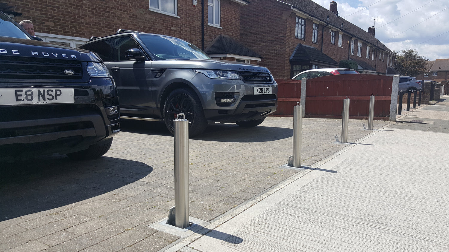 stainless steel lockable telescopic bollards installed across the entrance of a driveway