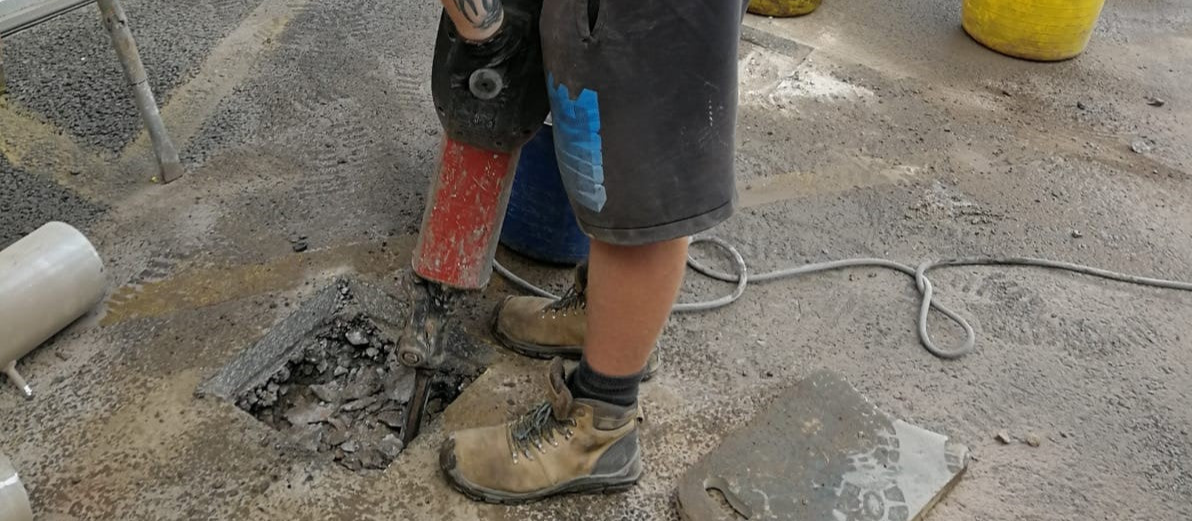 The excavation for a security bollard installation in front of commercial roller shutters
