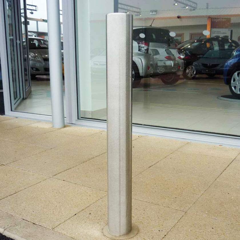 90mm diameter flat top stainless steel bollard on a retail park.