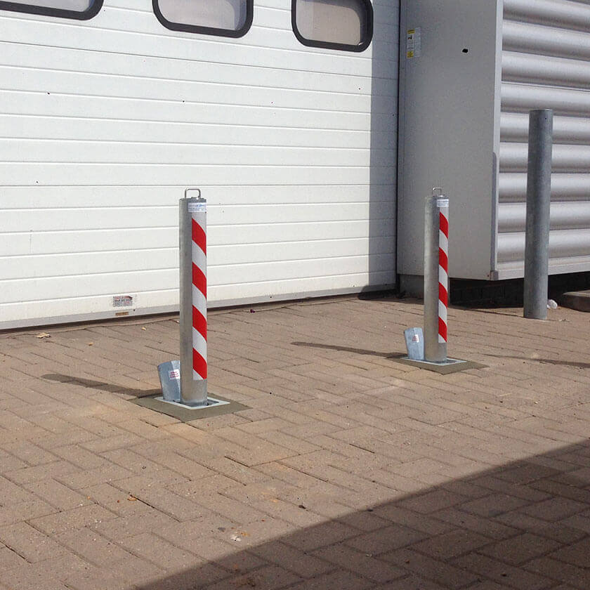 Heavy-duty, anti ram raid telescopic security bollards installed in front of roller shutters on a commercial estate