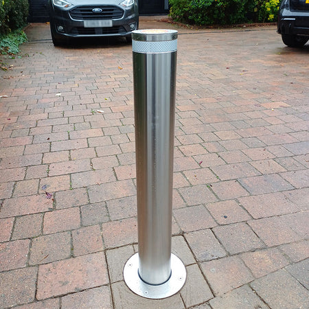 Stainless steel E-GO 800 x 114 automatic bollard installed on a block paved driveway.