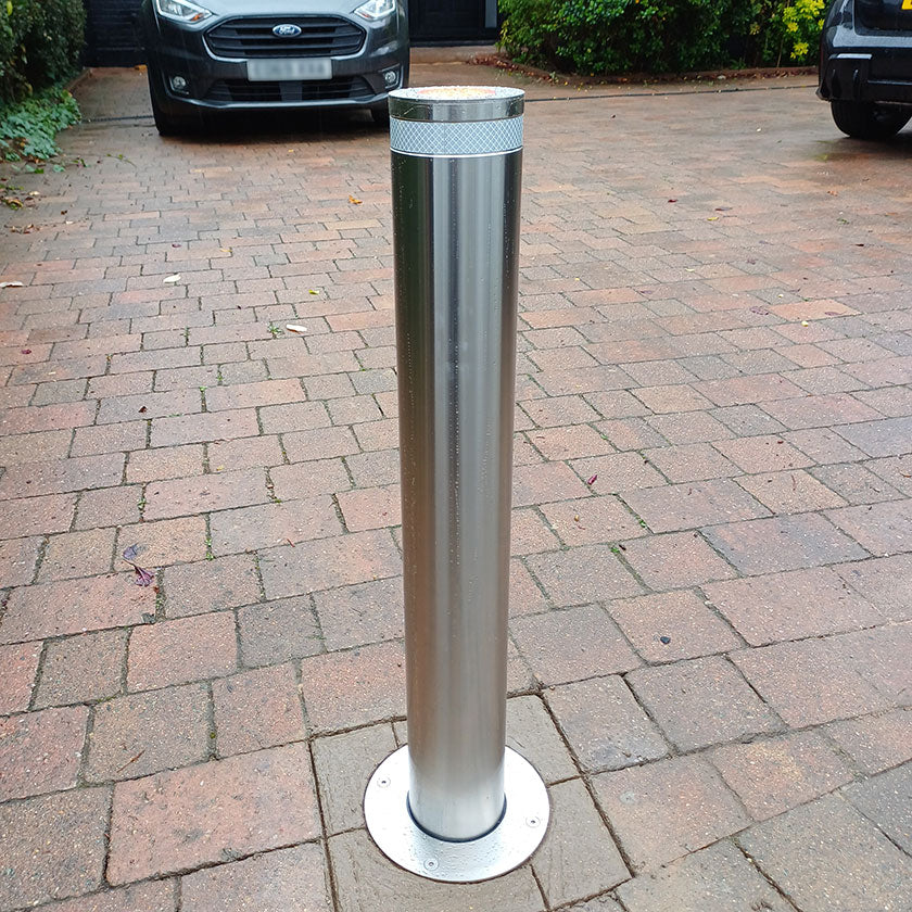 Stainless steel E-GO 800 x 114 automatic bollard installed on a block paved driveway.