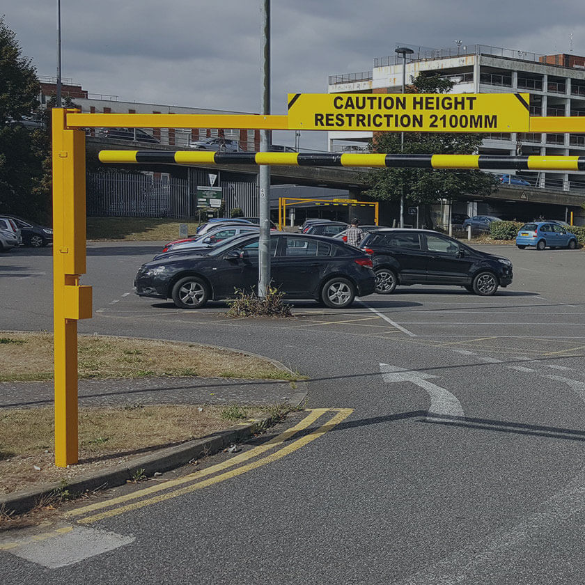 Height restriction barrier to control over height vehicles entering a retail car park.