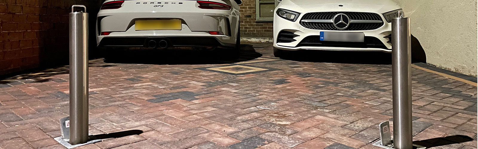 stainless steel lockable telescopic security bollards installed on a driveway to protect  a Porsche GT3 and a Mercedes AMG sports car