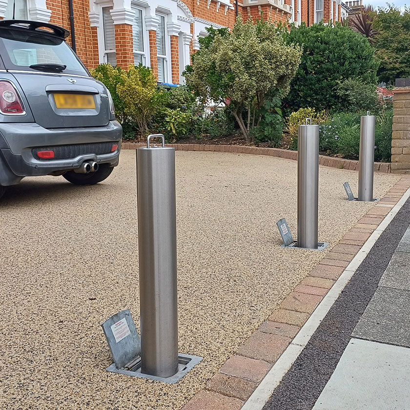 High security stainless steel telescopic bollards on a driveway with a car in the background
