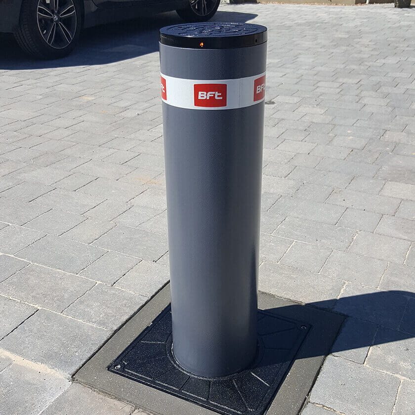 BFT Stoppy B 700  x 200mm automatic rising security bollard in a graphite grey finish, installed onto a block paved driveway