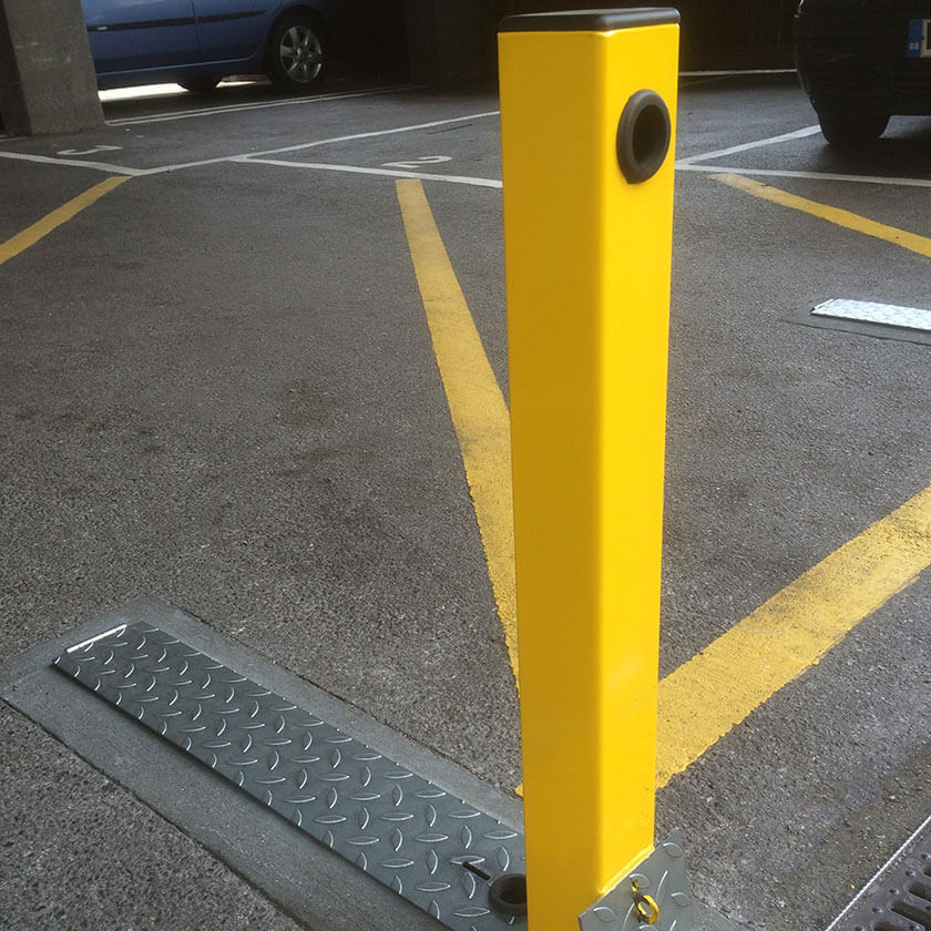 Hideaway fold down parking post in Yellow concealed inside an underground steel casing